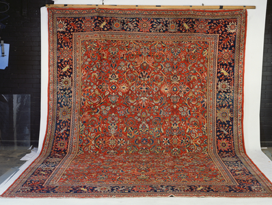 Mahal Carpet, the blood-red field with an all over design of flowing leafy floral vines enclosed by indigo palmette borders and multiple meander guard stripes