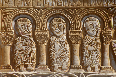 FRANCE. Occitanie. EASTERN PYRENEES. Saint Genis-des-Fontaines. Saint Genis Abbey. Monastery founded in 10th century. Facade and western gate. Lintel from 1019-1020. Detail of the three apostles. Romanesque art. Photography. Relief on rock