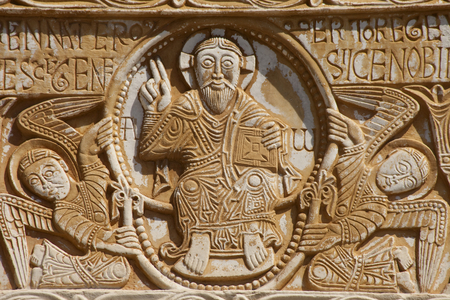 FRANCE. Occitanie. EASTERN PYRENEES. Saint Genis-des-Fontaines. Saint Genis Abbey. Monastery founded in 10th century. Facade and western gate. Lintel from 1019-1020. Christ in majesty inside an aureole holded by two angels. Romanesque art. Photography. Relief on rock