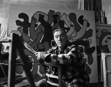 Fernand Leger straddeling a chair in front of an incomplete painting, Venice, Italy, 1950 (b/w photo)