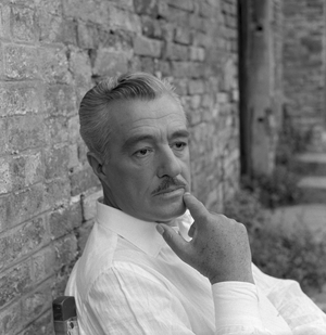 Italian actor Vittorio De Sica portrayed while sitting on a chair leaning agaist a wall, Venice 1958