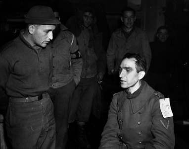 WWII:Near Florenville (Belgium) January 17, 1945: At Prisoner of War Camp No. 7, an American sergeant interrogates a German soldier who claims to have saved the lives of two injured tankers from the 11th DB US.