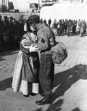 WWII:Marseille (Bouches du Rhone) 18 November 1945: The two millionth GI leaves France, an employee of the French Ministry of Information kisses him on both cheeks and offers him a bottle of Grasse perfume