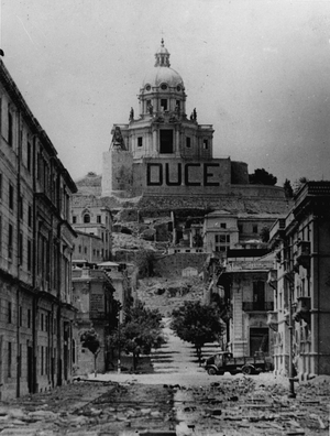 WWII:Messina (Sicily) Italy August 17, 1943: After the fall of the city, a city street with the Church of Christ the King in the background with the inscription “Duce” painted on the wall of its terrace