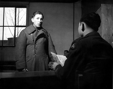 WWII:Bad Aibling (Germany) February 1946: A member of the US Army Interrogation Service questions a German prisoner of war and consults the list of people wanted to belong to the SS, Volksdeutscher or the NSDAP before starting the demobilisation process