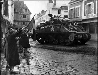 Second World War (1939-1945): an old woman greets with the tricolour flag a Sherman M4 tank of the 3rd American army during the liberation of the town of Nogent le Roi (Nogent-le-Roi) in August 1944. Photography.