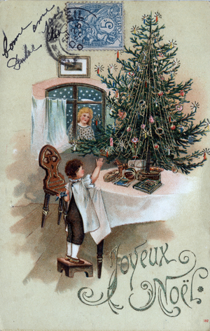 Christmas greeting card: a child in front of a Christmas tree poses on a table, observed by an angel in the window - Postcard dated 1905