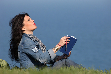 Woman reading the bible outside. Etretat France