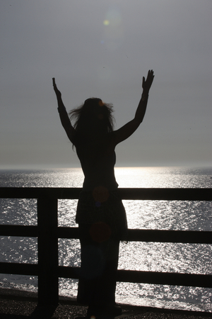 Woman praying at sunset. Etretat France