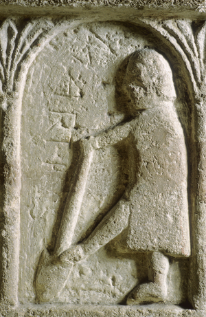 Digging soil with a spade, detail from the Norman font depicting the labour of the month for March (carved stone)