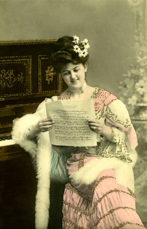 Pianist reading a score, very elegante young woman, flowers in the bun. 1910 approximately Historic photograph, woman reading notes, around 1910