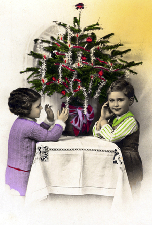 Christmas party: two children in front of a small Christmas tree decorates garlands.