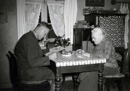 Old mother and son sitting at the table to read newspapers.