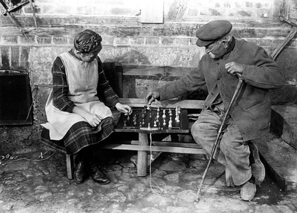Grandfather (Grandfather) playing chess games with his little daughter on a bench. Photography around 1925