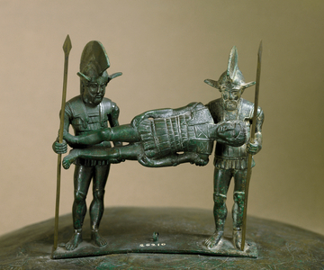 Etruscan antiquite: bronze cist handle composed of two warriors carrying a wound. From Preneste (Palestrina). 4th century BC. Dim. 30 cm Rome, Museo Nazionale di Villa Giulia