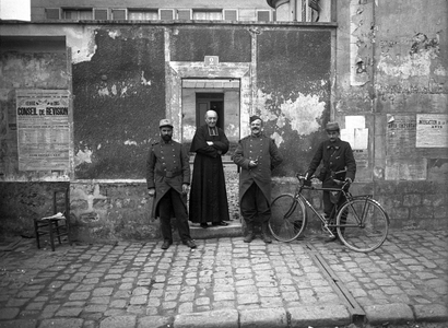 France, Ile-de-France, Paris (75): 3 soldiers and a cure pose in front of a poster of the 1915 revision board - military of the regiment N°19