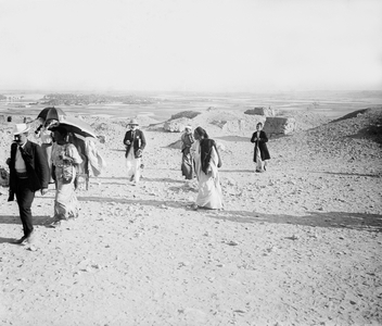 Egypt, Cairo: Cook cruise, suburbs of Cairo, tourists walk around the pyramids with umbrella and colonial hat, overlooking the flooded Nile Valley, 1900