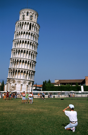 Leaning Tower of Pisa -Tuscany - Italy. A group of 3 visitors (tourists) is photographed by a fourth in front of the famous monument. Photography Patrice Cartier