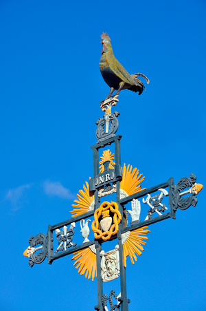Cross of missions (mission belief) in 1852 in Villegly (Aude, Occitanie) - this cross bearing the accessories that accompanied the torment of Jesus crucifie (instruments of the Passion), officially designated as the Arms of Christ (Arma Christi: hammer, nails, pincers, crown of thorns, ladder, spear, cup of bitter drink - field- sponge, linen with printed face...) is surmounted by a copper rooster. The Christians see it as a symbol of resurrection or the evocation of the “rooster of St. Peter”, others incline for an addition dating back to 1905 and intended to “republicize” the religious monument by overcoming it with a national and republican symbol during the separation of Church and State in Fance. Photo by Patrice Cartier -