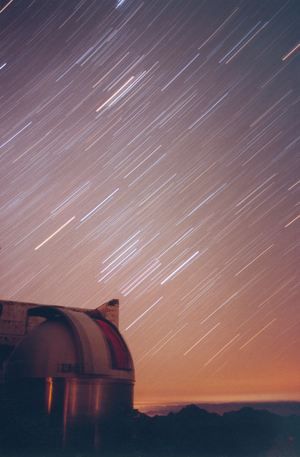 Star Trains - Orion Constellation at the Pic du Midi - Pic du Midi observatory - Orion star trails - The dome of the T60 faces the large constellation Orion. The curvature of the stars makes it possible to determine the Celestial Ecuador. Photographic pose of 30 minutes obtained in September 1995. T60 dome is facing Orion constellation on this 30 minutes exposure image. The long exposure enhances the colors of the stars