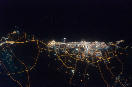 Dubai Night View from Space - City of Dubai at night - The coasts of the Emirates of Dubai with the Palm Island of Jumeirah, seen at night from the International Space Station (ISS) on September 11, 2009. This nighttime astronaut photograph of the city of Dubai was taken at approximately 2 a.m. local time on September 11, 2009. Orange sodium vapor lights trace the major highways and street grid in and around the metropolitan area, while grey - white mercury vapor lamps fill in the commercial and residential areas. The lighted islands and peninsula of Palm Jumeirah are clearly visible along the coastline. A spiral pattern of lights on the southeastern fringe of the urban area is a camel racetrack. Nighttime images like these are useful to climate modelers, urban planners, and geographers as they allow for simple definition of urban (densely lit) and rural (sparely lit) areas