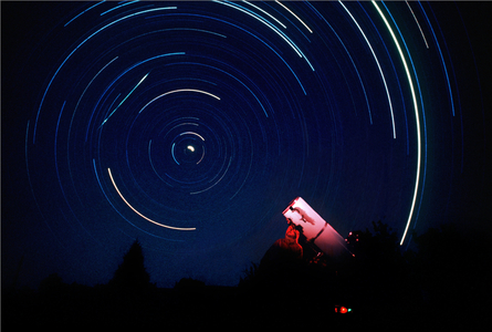 Shooting star and amateur astronomer - Meteor and observer - The straight diagonal streak in the upper left of this photo is a meteor. The curved streaks are the trails of stars that were recorded during the 5.5 hour time exposure on a fixed tripod. An observer at his telescope is illuminated with a red flash in the foreground