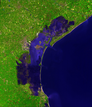 Venice and its lagoon - satellite view - 09/12/2001 Venice stretches out across numerous small islands in a marshy lagoon along the Adriatic Sea in northeastern Italy. The saltwater lagoon stretches along the shoreline between the mouths of the Po (sth) and Piave (nth) Rivers. This image from the Advanced Spaceborne Thermal Emission and Reflection Radiometer on the Terra satellite shows the watery city in spectacular detail, using false - color image enhancements that bring out the details of water and vegetation. The heart of Venice is on the island known as the Rialto, the largest island in the lagoon, which is just southwest of the center of this scene. The city is somewhat protected from the open sea by a row of sandbanks known as the Lido (east of Rialto), however, the city is continually under threat of flooding and erosion, and has been experimenting with tidal control measures for more than a thousand years. Four hundred bridges cross the labyrinth of canals that form the 120 islands of Venice. All traffic in the city moves by boat. Venice is connected to the mainland, 4 km (2.5 miles) away, by ferries as well as a causeway for road and rail traffic. Rialto is split by the Grand Canal, which follows the path of an ancient river. The Grand Canal winds through the city for about 3 kilometers (about 2 miles), dividing it into two almost equal sections. According to tradition, Venice was founded in 452, when the inhabitants of Aquileia, Padua, and several other northern Italian cities took refuge on the islands of the lagoon from the Teutonic tribes invading Italy at that time