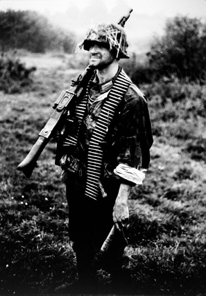 German soldier carrying an MG34 machine gun with belt ammunition and stick grenade (b/w photo)