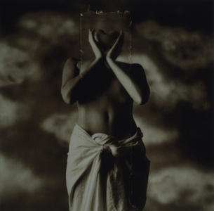 Semi-dress woman holding rectangle with heart shape in front of face