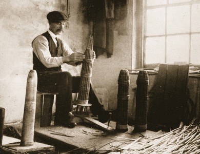 Making wicker cases for British shells: fashioning the 'baskets', and a model of a shell to ensure a good fit, from 'The Illustrated War News' (b/w photo)