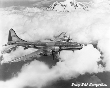 United States: c. 1944 - A U.S. Air Force Boeing B-29 Superfortress bomber flying above the clouds and mountains.
