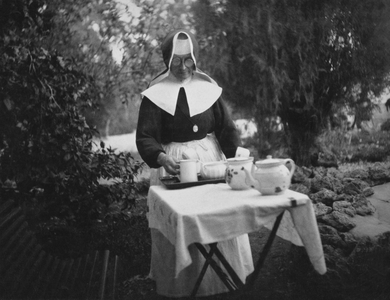Haifa, Palestine : c. 1930 - A German Catholic nun at the German Hospice preparing out a tea setting outdoors