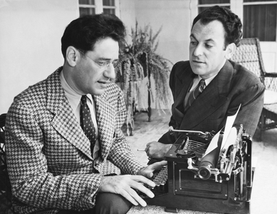 United States: May 6, 1937
Noted playwrights George S. Kaufman and Moss Hart with Kaufman at a typewriter. The two men collaborated on numerous plays.