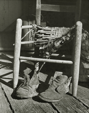Close-up of a pair of shoes next to a broken chair on a mountain cabin porch