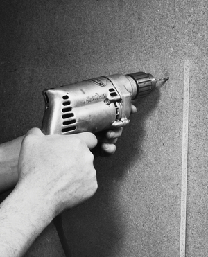 Close-up of a person's hands drilling into a wall