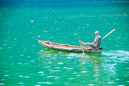 Vietnamese transport: Man rowing boat with feet on the Hoa Binh Reservoir, Vietnam