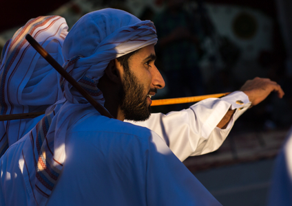 Men dressed in white dancing with sticks during a wedding ceremony, Hormozgan, Bandar-e Kong, Iran (photo)