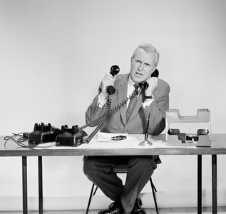 Businessman using two telephones