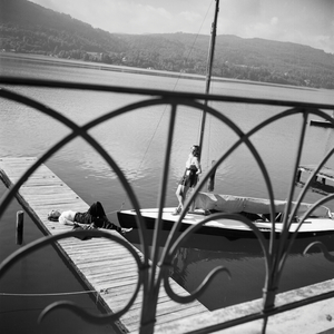 Two young woman tanning on the shore of a lake, one on a boardwalk, the other on a sailing boat, Germany 1930s (b/w photo)