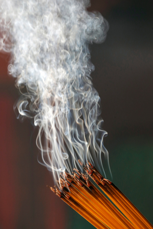 Ha Chuong Hoi Quan Pagoda, Young Chinese woman praying with big burning incense sticks in her hand, Ho Chi Minh City, Vietnam, 2019 (photo)