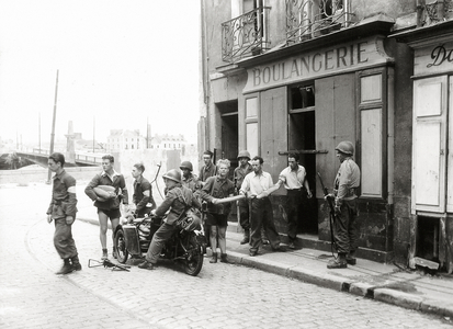Outside the bakery of Marcel Baud at 3 rue Grande Biesse is a group of male civilians and three GIs, Nantes, Normandy, France, August 1944 (b/w photo)