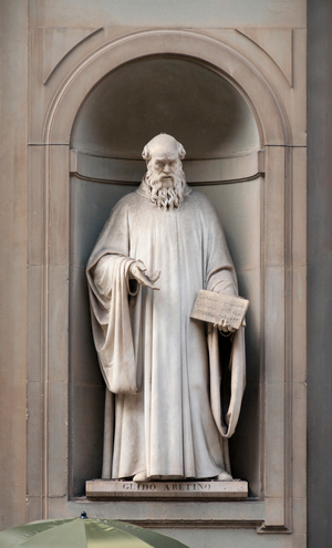 Italy: Guido Aretino (Guido of Arezzo, 991/992 - 1033), Italian musical theorist and the inventor of modern musical notation. 19th century statue outside the Uffizi Gallery, Florence, Italy. Sculpted by Lorenzo Nencini. (2016)