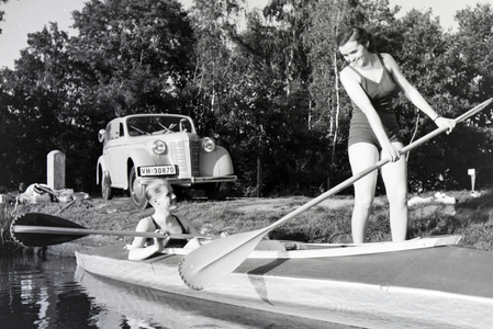 Young couple paddling in a boat on a lake near the river, Germany 1930s (b/w photo)
