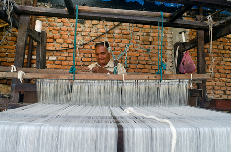 Nepali traditional weaver operating a handloom (foot-treadle floor loom), Kahare, Chalnakhel, Kathmandu Valley, Nepal (photo)