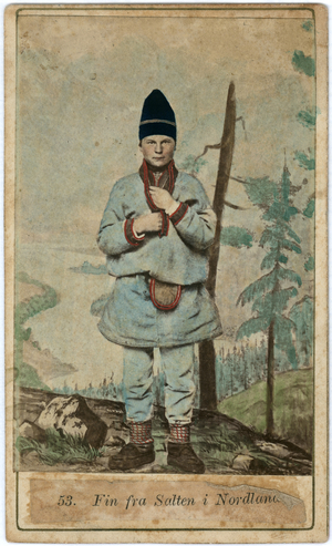 Full length portrait of a boy wearing heavy–weight tunic and trousers, a purse at his belt and a high hat.  He is set against a landscape, which is looks like a studio background, c.1870s (hand-tinted albumen print)
