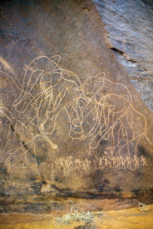 Rock engraving depicting a herd of moving elephants and under a group of men - Tassili n'Ajjer, Tadart Rouge, Tassili n'Ajjer, Algeria, 2000 (photo)