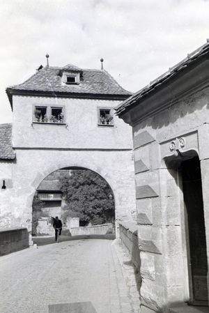 A cyclist driving through one of the many historical archways in Rothenburg ob der Tauber, Germany 1930s (b/w photo)