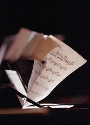 Sheet music on the stand of a piano. Reflection