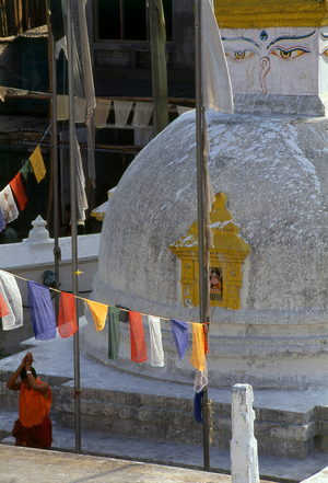 Nepal: A monk prays next to a small stupa at Bodhnath (Boudhanath), Kathmandu