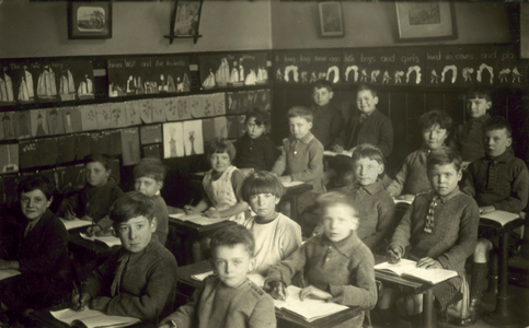 Boys and girls in school classroom (b/w photo)